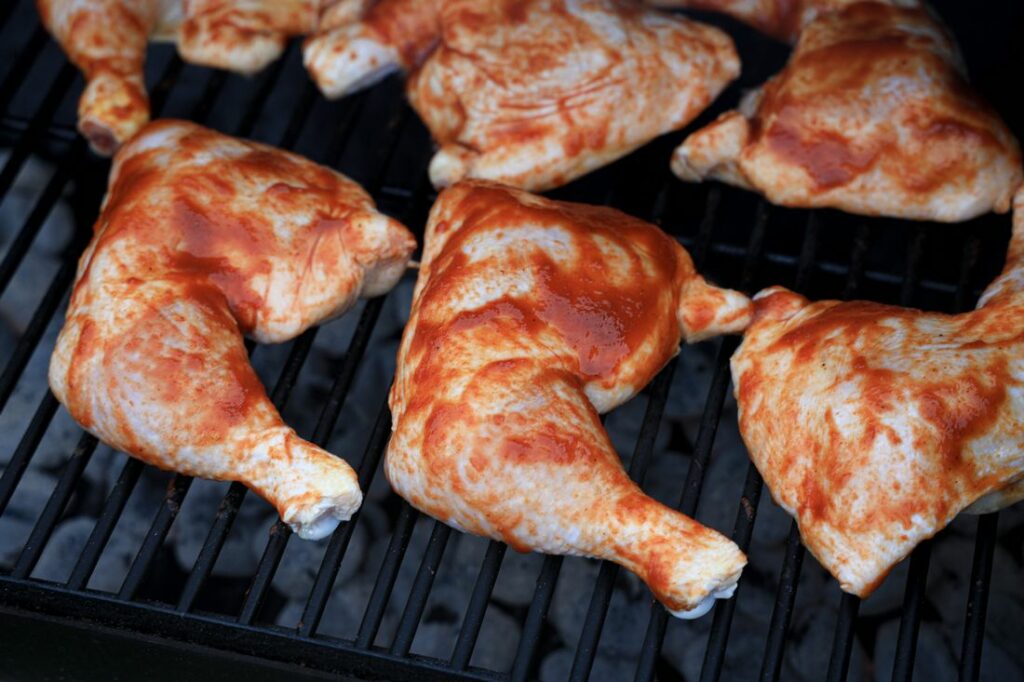 Chicken quarters on the grill with barbecue sauce