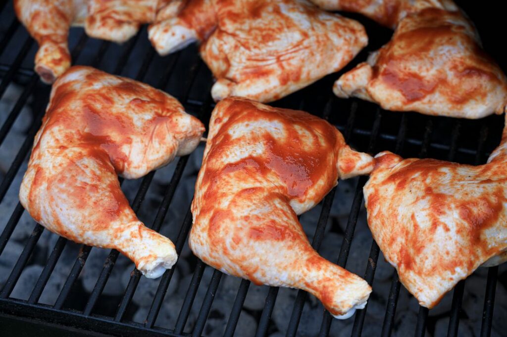 Chicken quarters on the grill with barbecue sauce