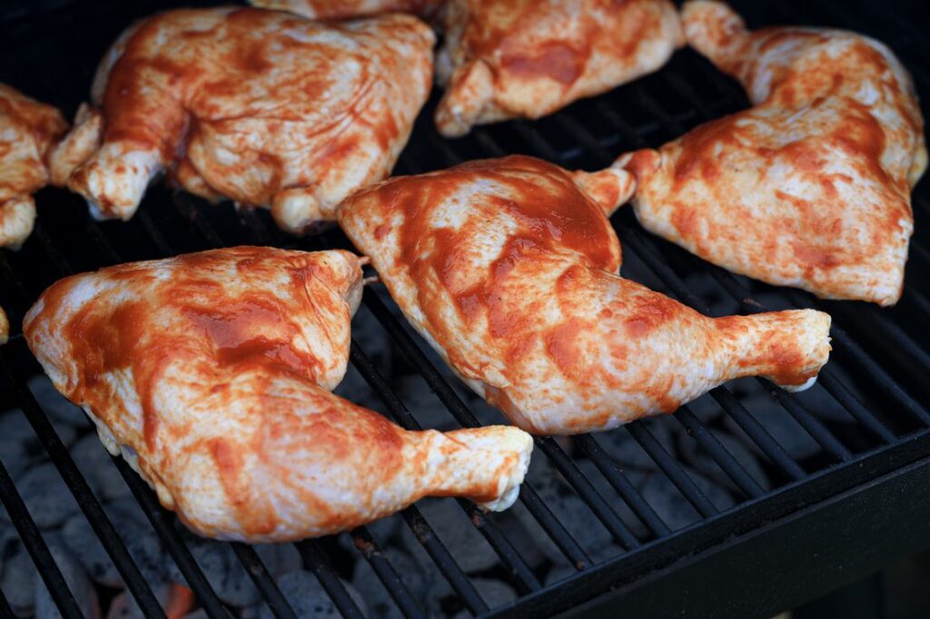Chicken quarters on the grill with barbecue sauce