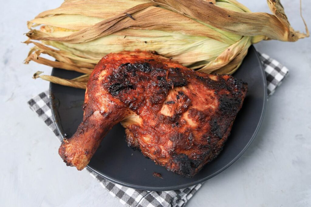 BBQ Picnic Chicken on a gray plate with gray plaid napkin on a concrete backdrop