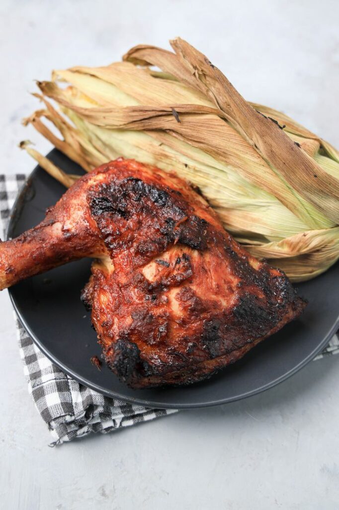 BBQ Picnic Chicken on a gray plate with gray plaid napkin on a concrete backdrop