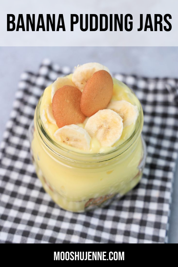 Banana pudding glass mason jar on a gray plaid napkin on a concrete backdrop