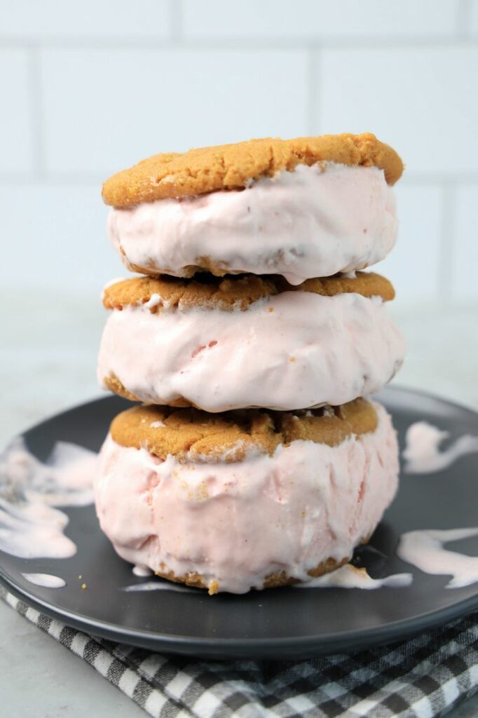 Strawberry Peanut Butter Ice Cream Sandwiches on a gray plate with a gray plaid napkin on a concrete backdrop