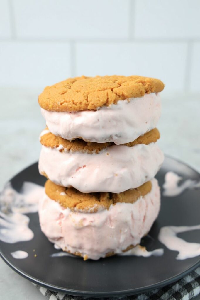 Strawberry Peanut Butter Ice Cream Sandwiches on a gray plate with a gray plaid napkin on a concrete backdrop