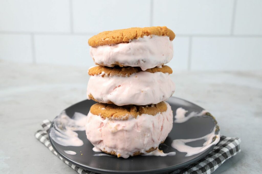 Strawberry Peanut Butter Ice Cream Sandwiches on a gray plate with a gray plaid napkin on a concrete backdrop