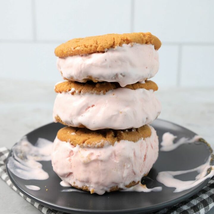 Strawberry Peanut Butter Ice Cream Sandwiches on a gray plate with a gray plaid napkin on a concrete backdrop