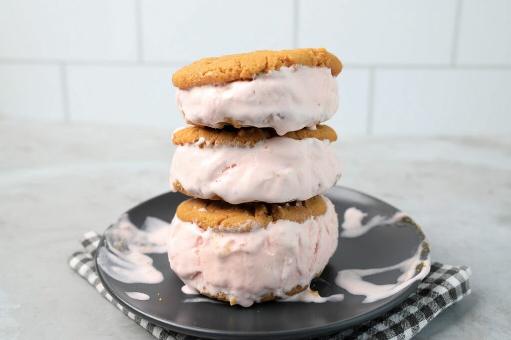 Strawberry Peanut Butter Ice Cream Sandwiches on a gray plate with a gray plaid napkin on a concrete backdrop