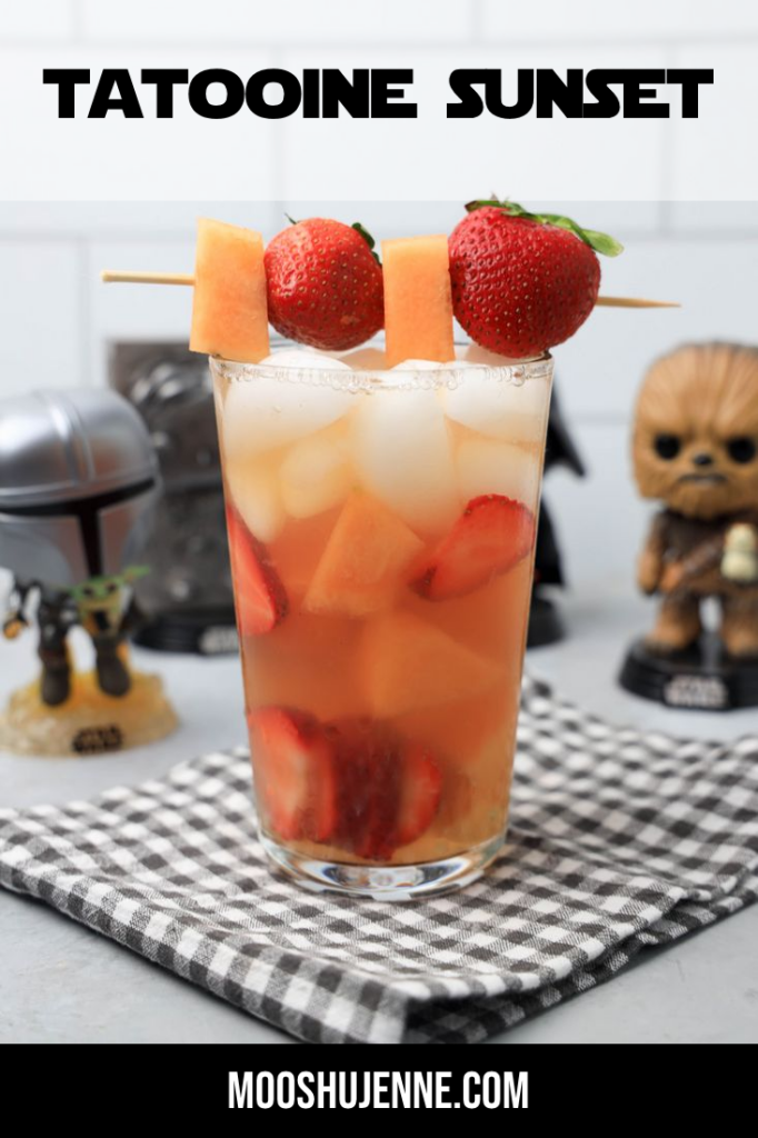 Tatooine sunset drink with cantaloupe and strawberries in a glass on a gray plaid napkin on a concrete backdrop.