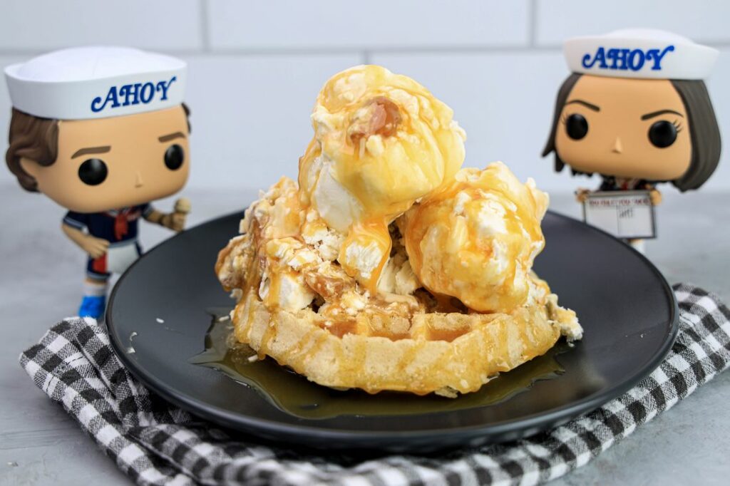 Butterscotch ice cream on a waffle on a gray plate on a grey plaid napkin on a concrete backdrop with stranger things funko pops