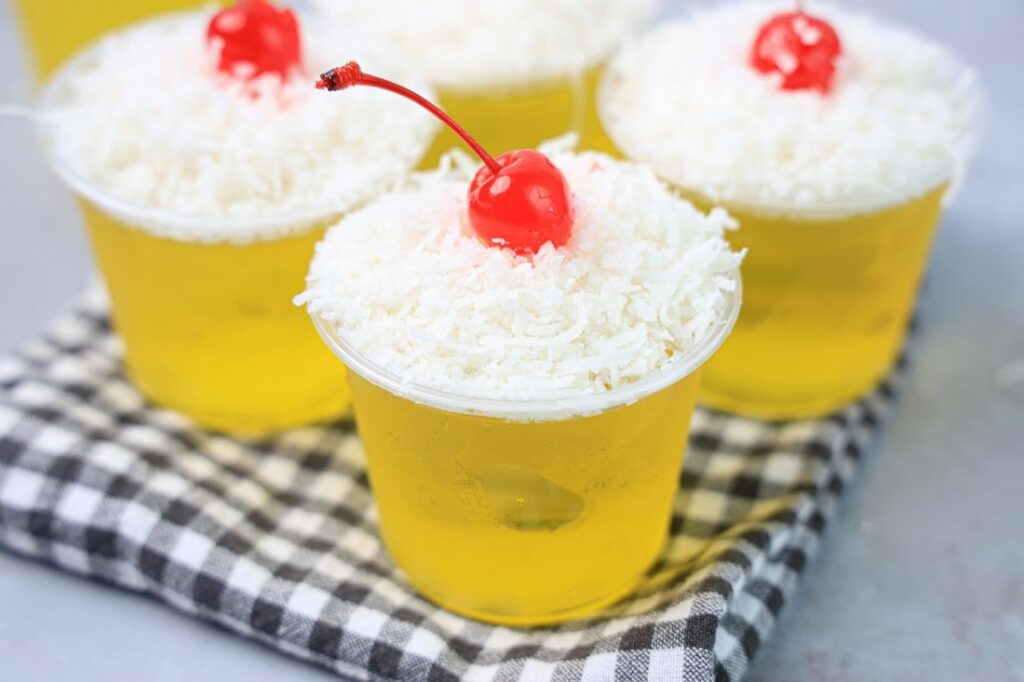 Pina colada jello shot topped with coconut and a cherry.