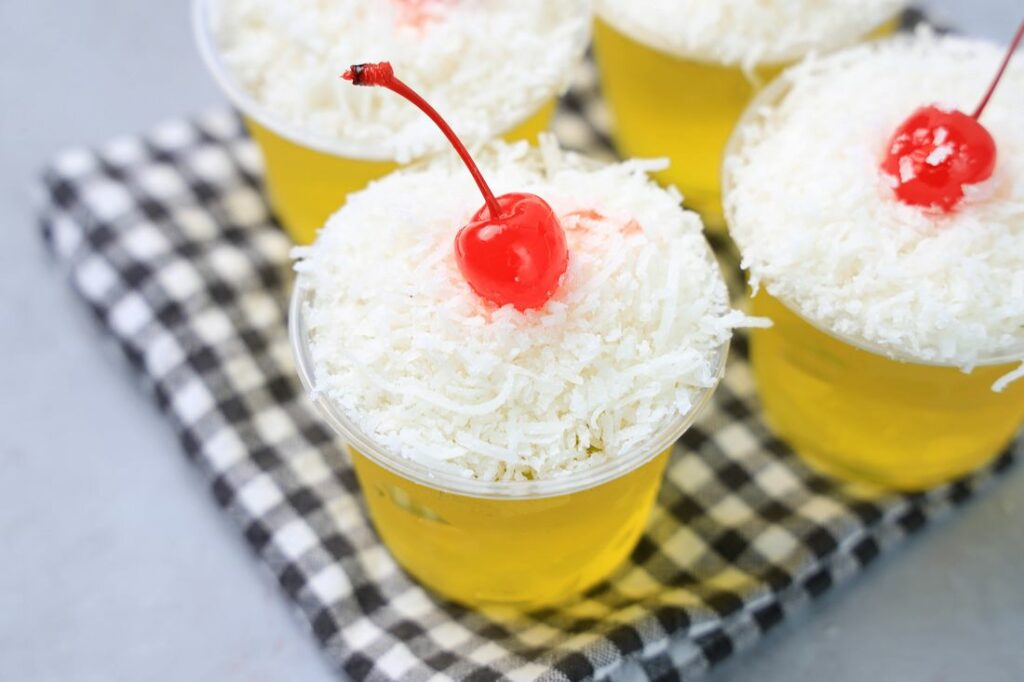 Pina colada jello shot topped with coconut and a cherry.