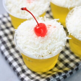 Pina colada jello shot topped with coconut and a cherry.