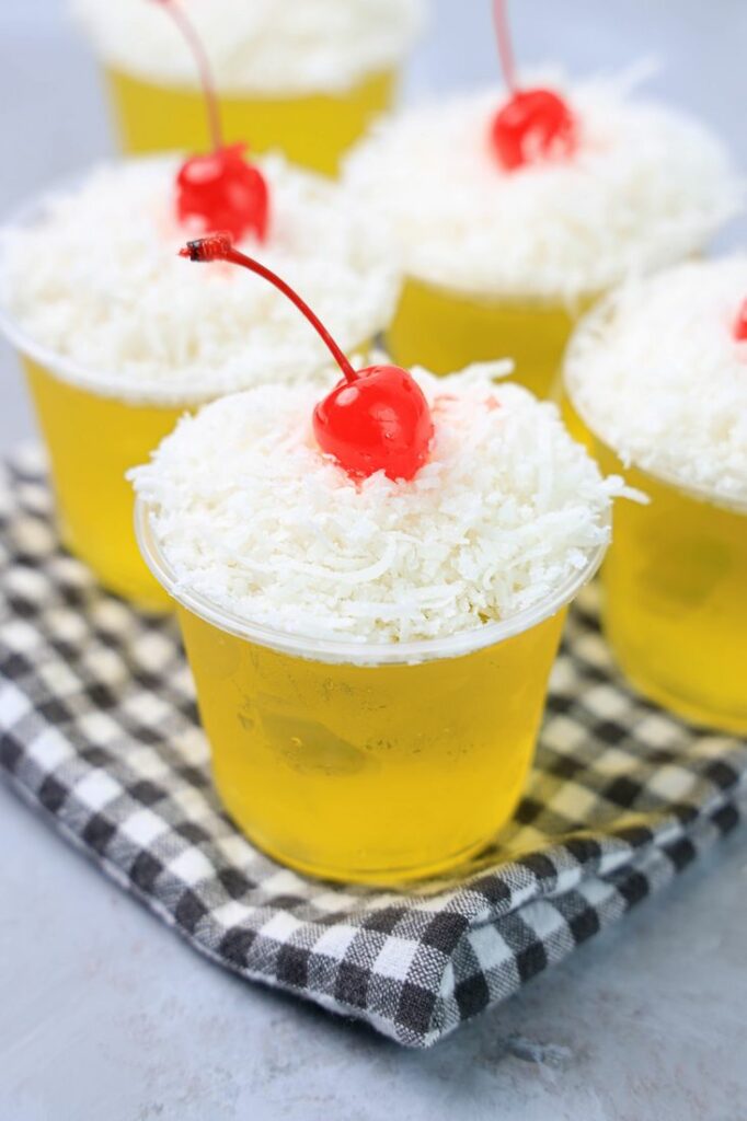 Pina colada jello shot topped with coconut and a cherry.