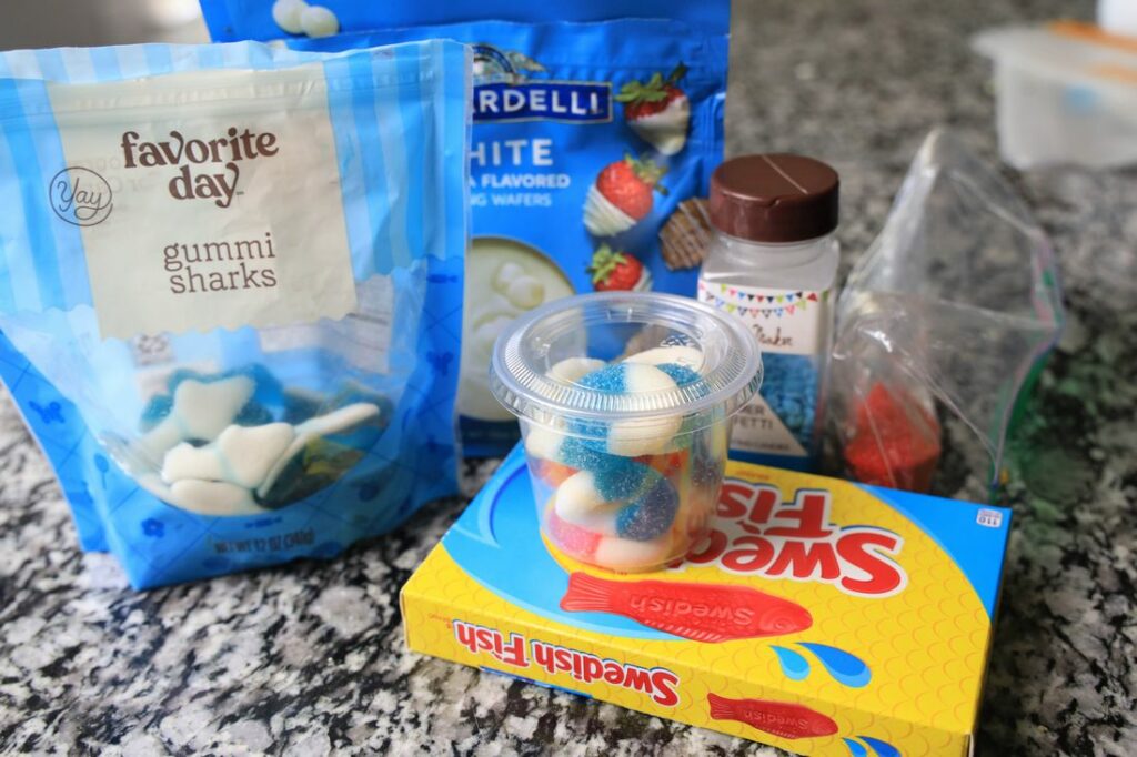 shark gummies, swedish fish, gummy rings, and white chocolate items to make shark week popcorn.