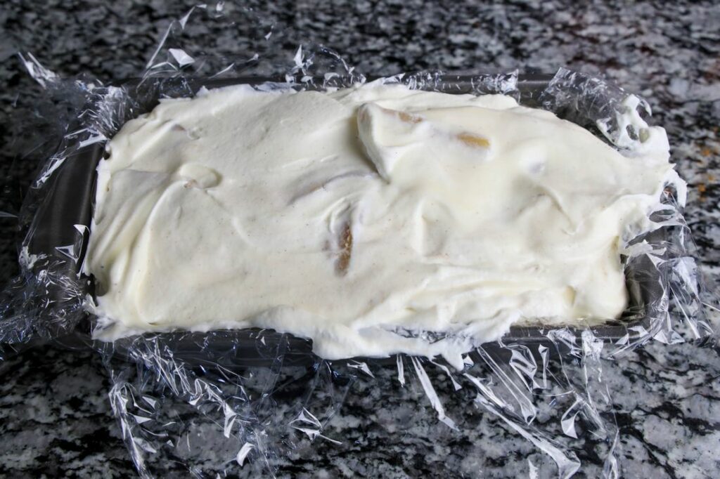 Apple pie ice cream in a loaf pan with plastic wrap.