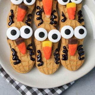 Nutter Butter Owls on a white plate on a plaid napkin with concrete backdrop