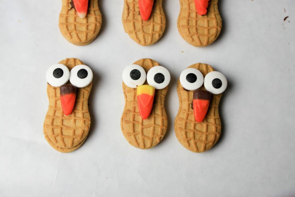 Nutter butter cookies, candy corn, candy eyes, and black sparkle gel on parchment paper.