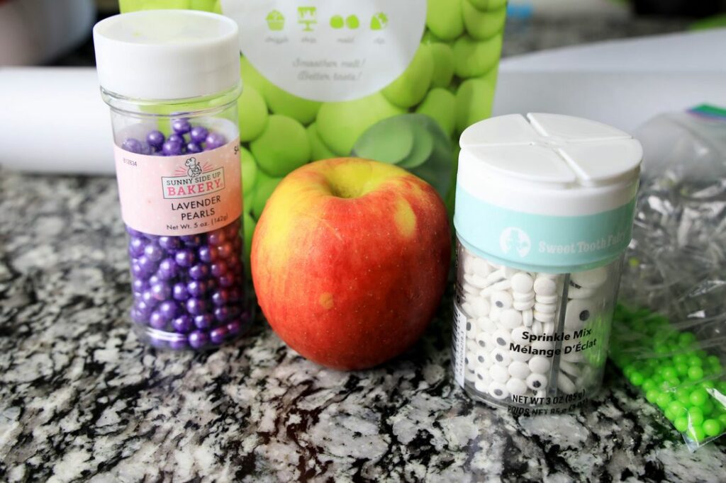 Candy eyes, sprinkles, and apples shown to make the candied apples.