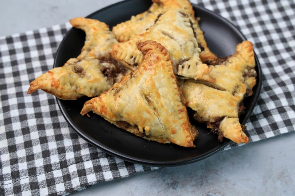 Hocus Pocus Savory Witch Hat Pies on a black plate with a gray plaid napkin on a concrete backdrop