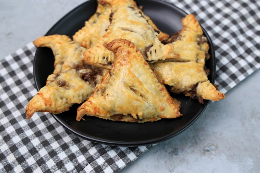 Hocus Pocus Savory Witch Hat Pies on a black plate with a gray plaid napkin on a concrete backdrop