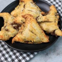 Hocus Pocus Savory Witch Hat Pies on a black plate with a gray plaid napkin on a concrete backdrop