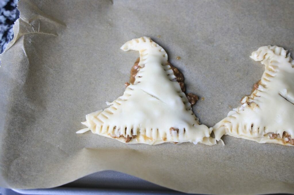 Hocus Pocus savory witch hat pies on parchment paper ready for baking.