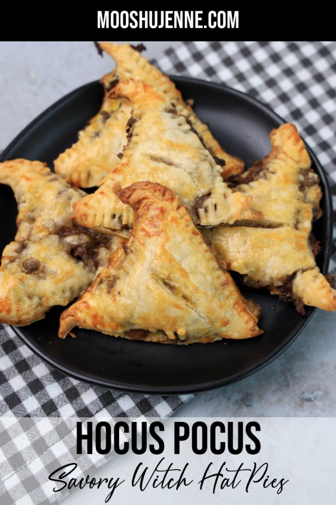 Hocus Pocus Savory Witch Hat Pies on a black plate with a gray plaid napkin on a concrete backdrop