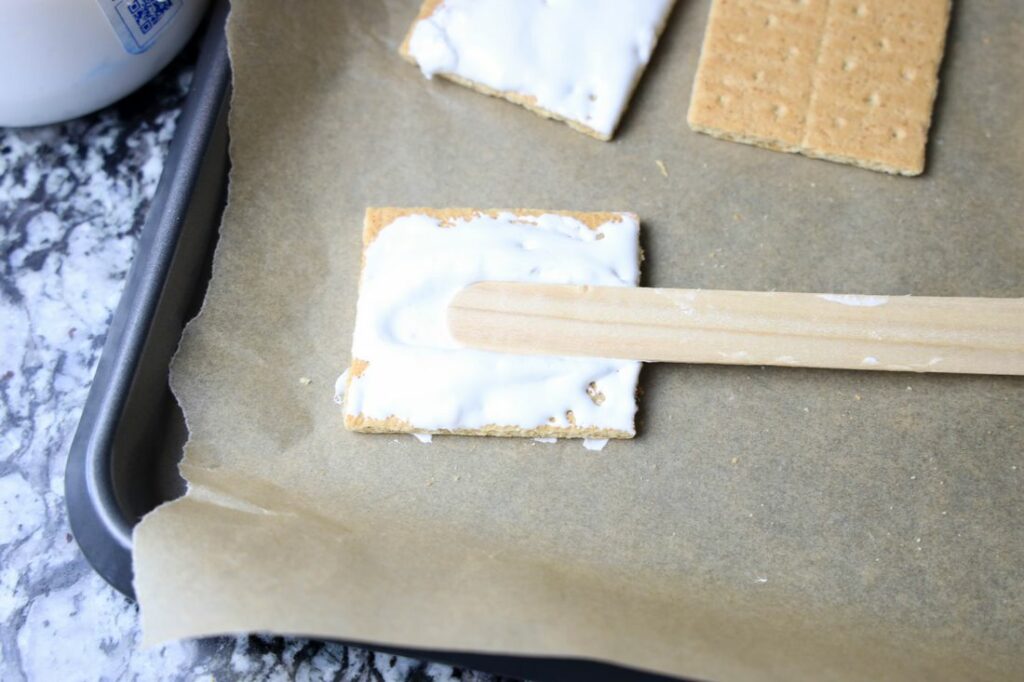 Graham cracker with marshmallow fluff and pop stick in center.