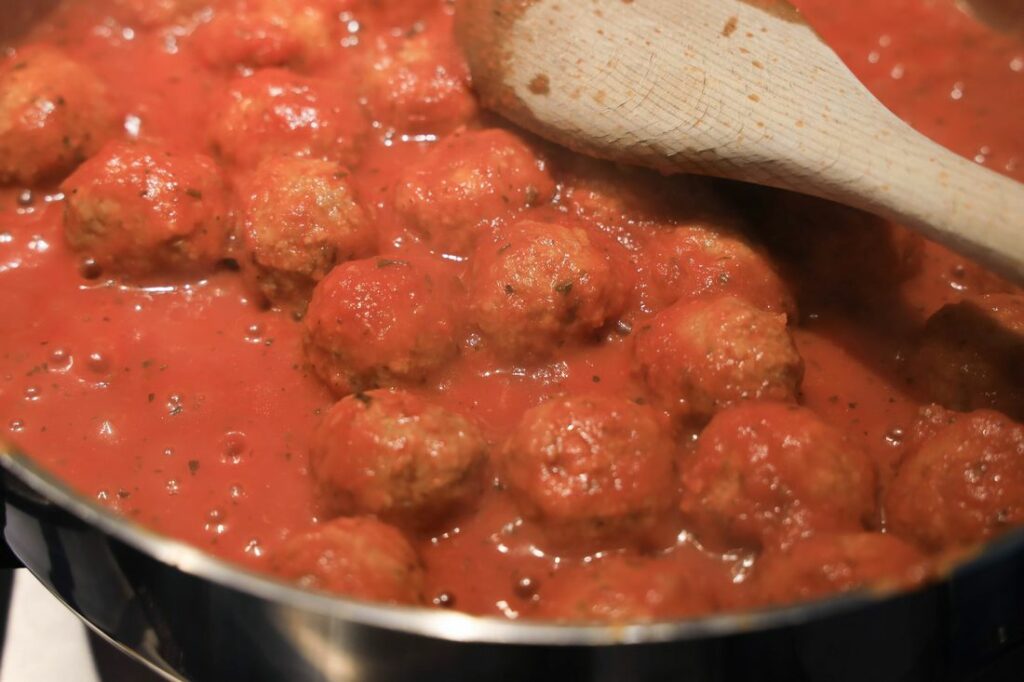 Meatballs simmering in spaghetti sauce.