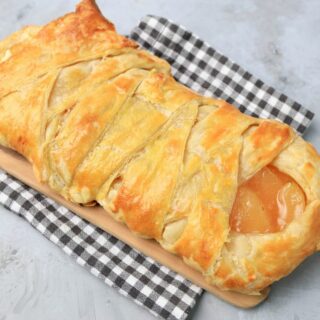 Apple Pie Cream Cheese Braid on a wood board on a plaid napkin.