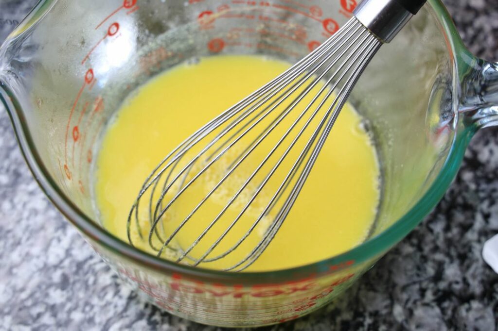 Yellow jello in a bowl being mix for jello shots.