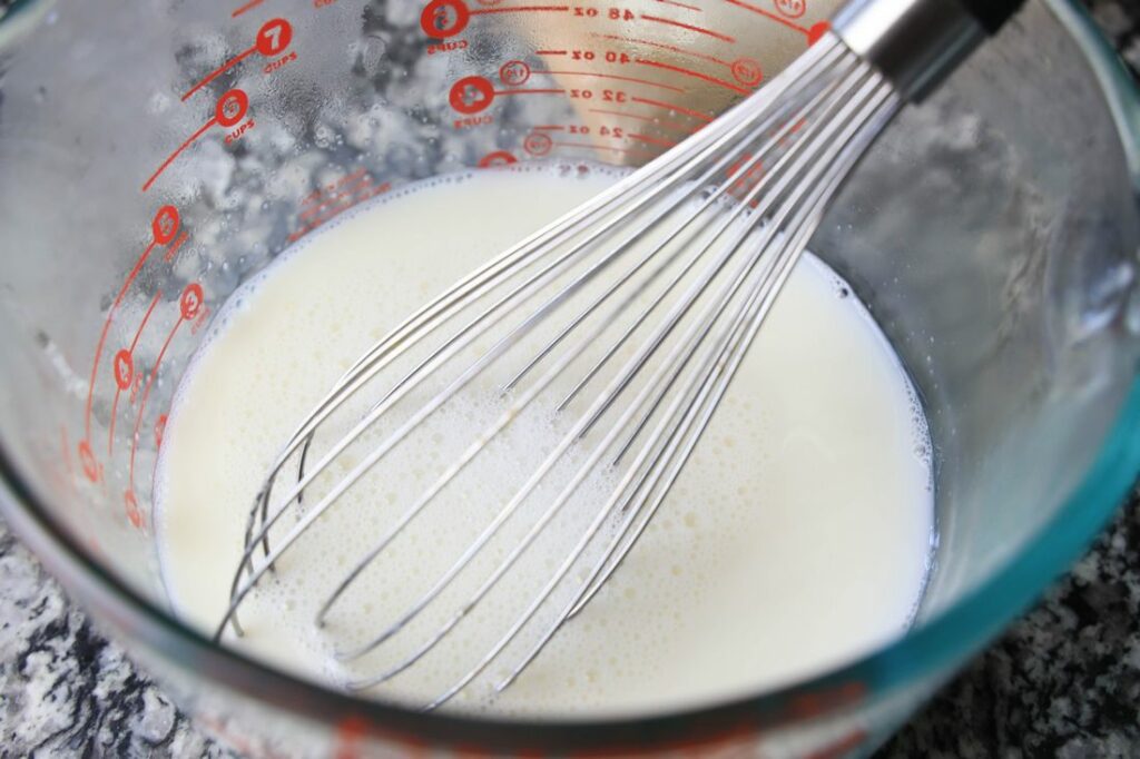 Mixing sweetened condensed milk and hot water in a bowl