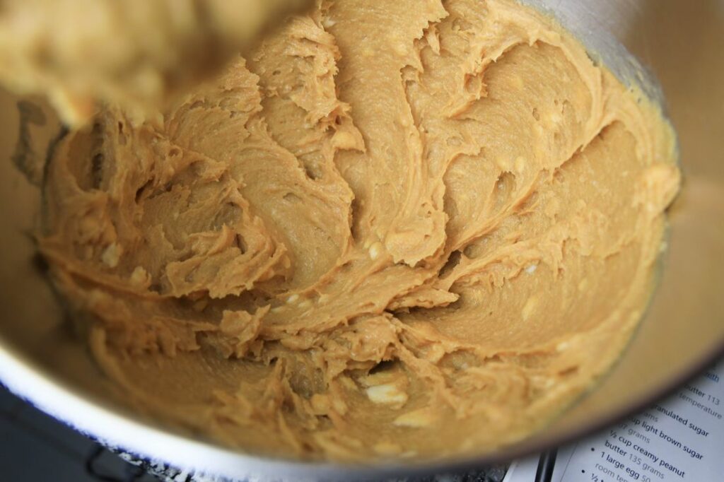 Mixed peanut butter dough in a kitchen aid mixer bowl.