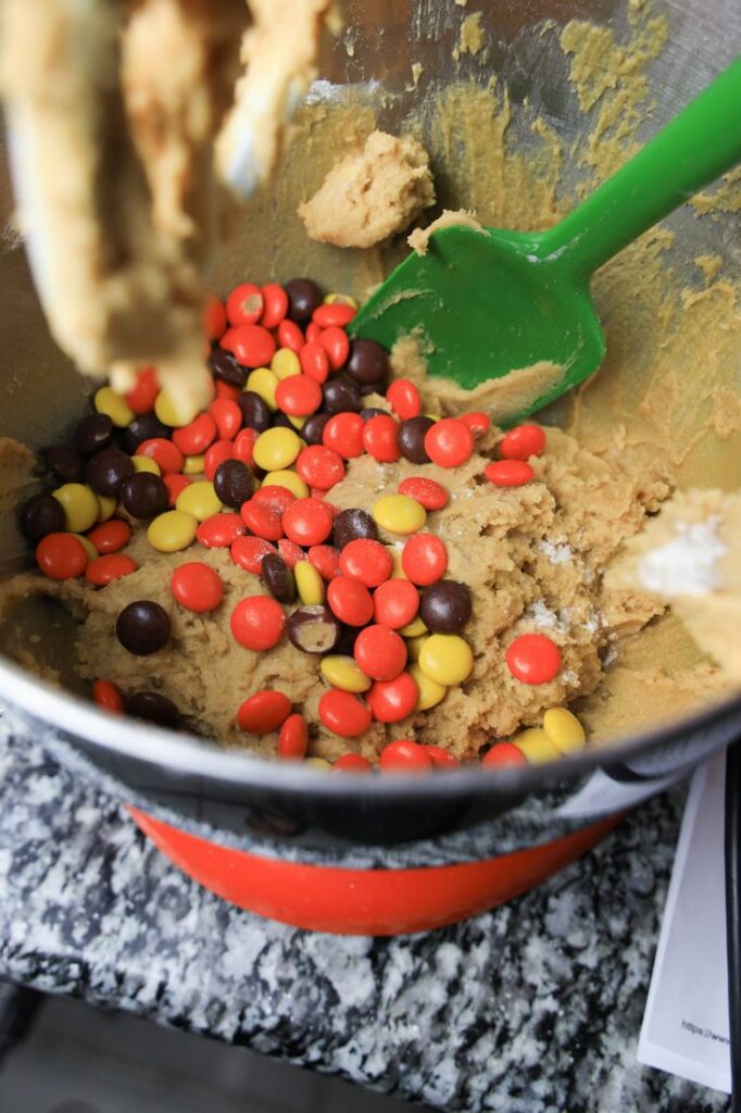 Reese pieces in the peanut butter dough inside the stand mixer.