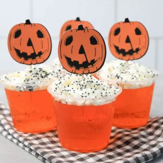 Halloween Movie Pumpkin Jello Shots that are orange topped with whipped topping and black sprinkles. With the 1978 Halloween Movie Pumpkin Topper.