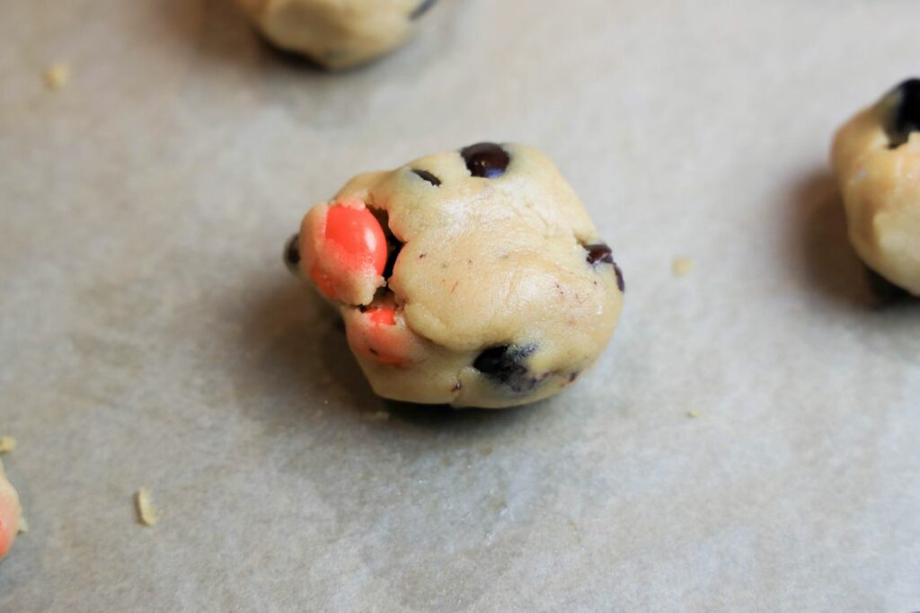 Peanut Butter M&M cookie rolled on a parchment lined baking sheet.