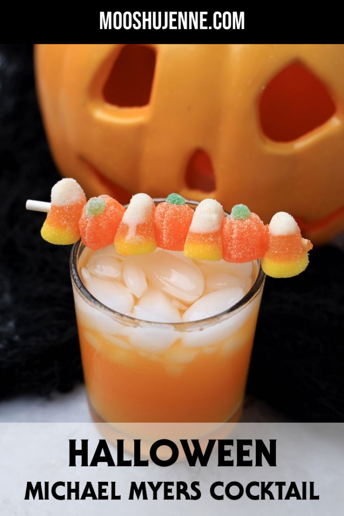 Halloween Michael Myers Cocktail with orange juice and orange soda. Topped with candy corn and pumpkin gummies. With the original myer's pumpkin in the back.