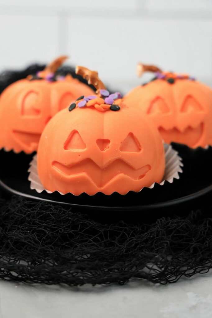 Jack O' Lantern Hot Chocolate bomb on a black plate with black mesh.