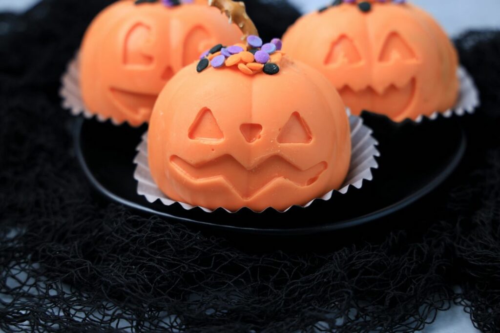 Jack O' Lantern Hot Chocolate bomb on a black plate with black mesh.