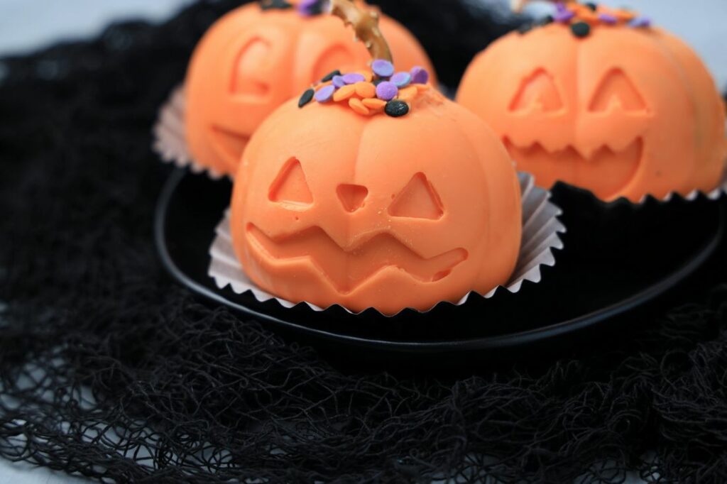 Jack O' Lantern Hot Chocolate bomb on a black plate with black mesh.