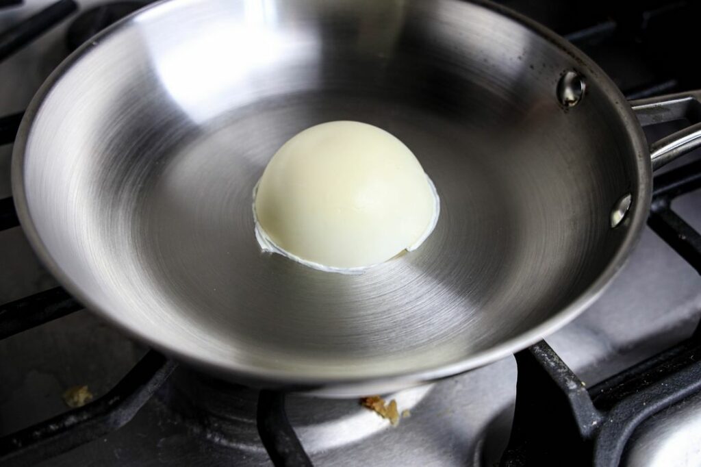 White chocolate dome being heated in a pan.