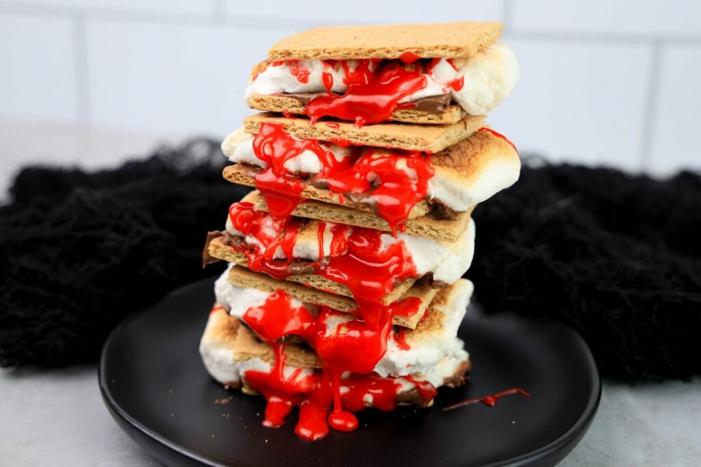 Graham crackers with hershey's chocolate, marshmallows, and red cookie icing.