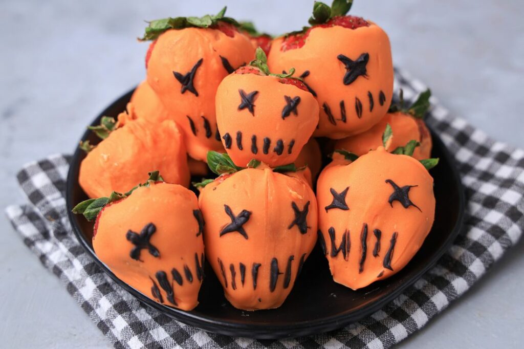 Strawberries covered in orange candy melts and decorate with black candy melts to look like the pumpkin from Trick 'R Treat.