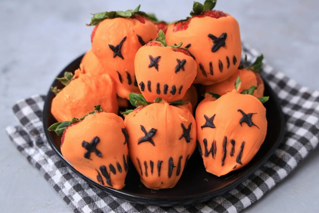 Strawberries covered in orange candy melts and decorate with black candy melts to look like the pumpkin from Trick 'R Treat.