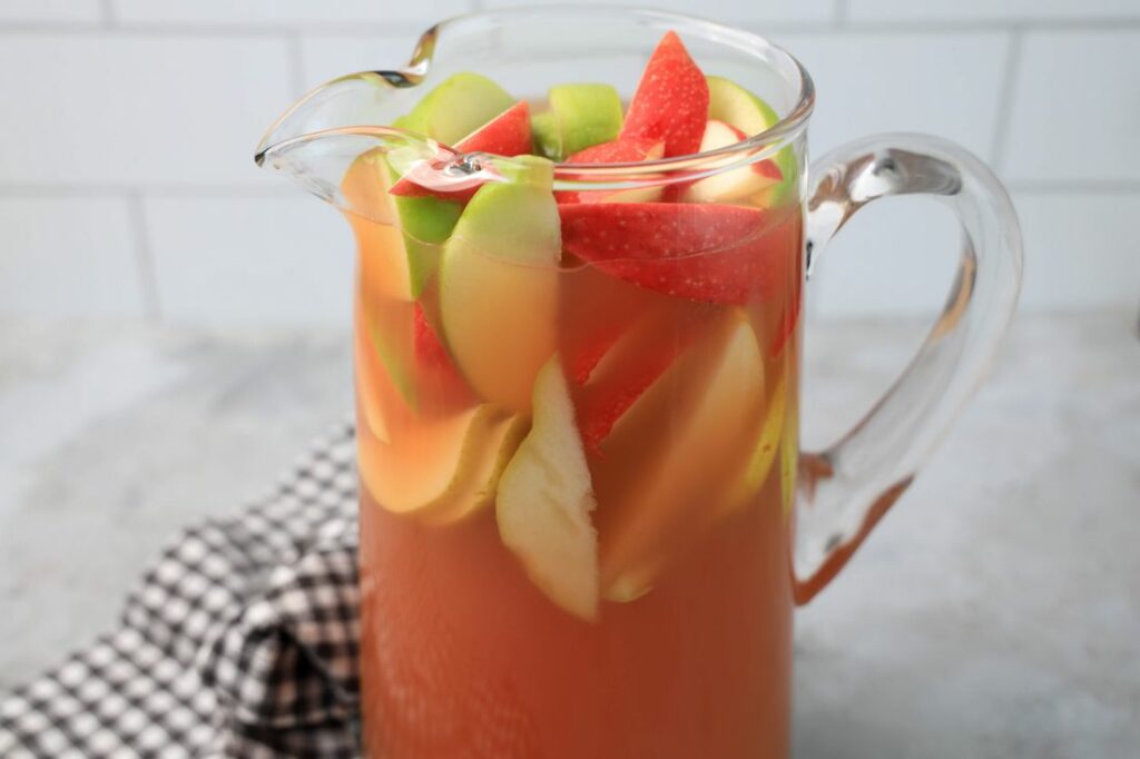 Punch in a glass pitcher with honey crisp apples and granny smith apples.