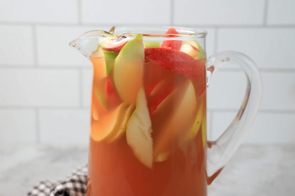 Punch in a glass pitcher with honey crisp apples and granny smith apples.