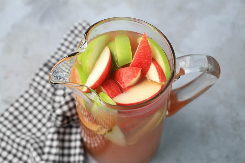 Punch in a glass pitcher with honey crisp apples and granny smith apples.