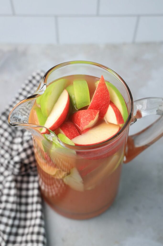 Punch in a glass pitcher with honey crisp apples and granny smith apples.