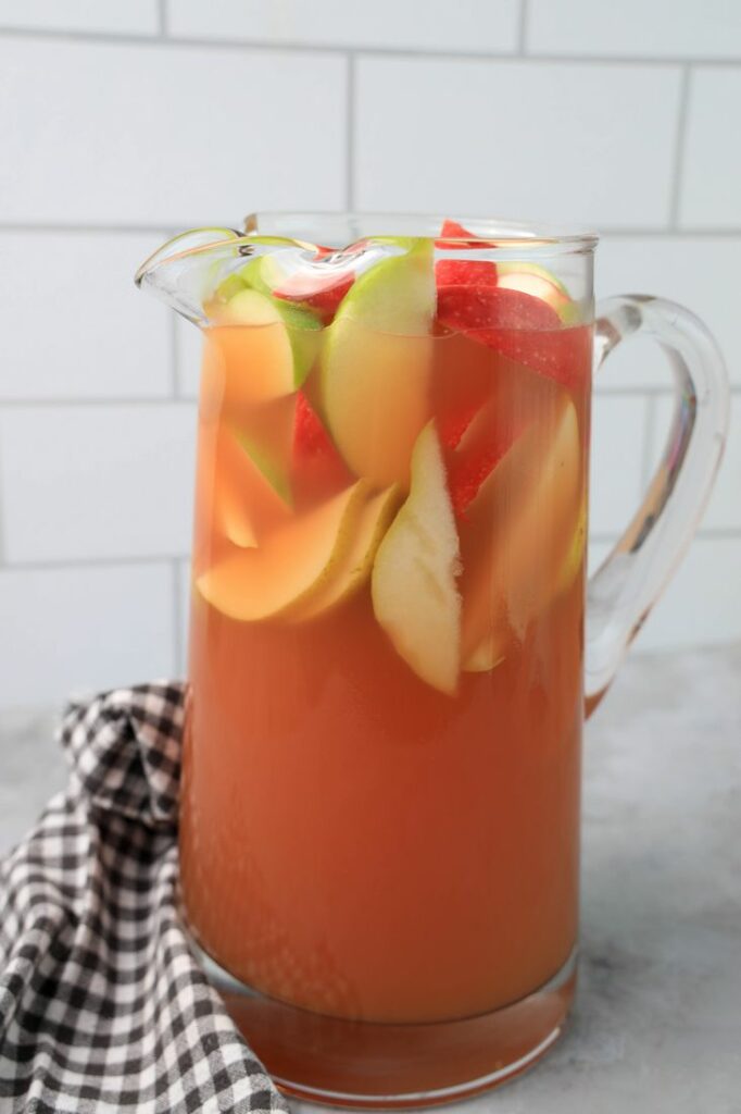 Punch in a glass pitcher with honey crisp apples and granny smith apples.