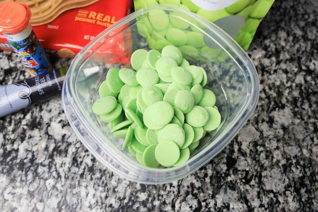 Light green candy melts in a plastic bowl on a counter top.